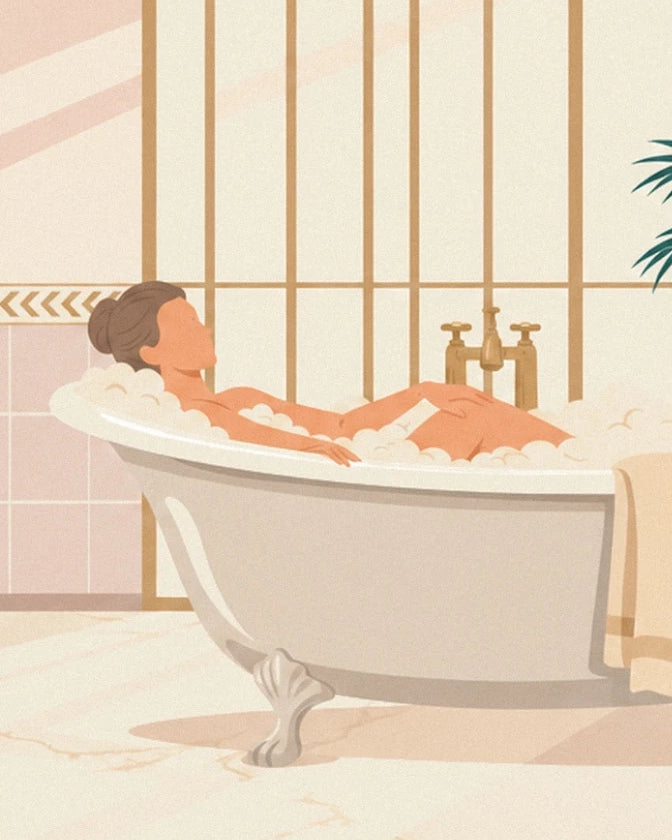 La femme au chignon allongée dans sa baignoire sur pieds, mousse et robinet doré