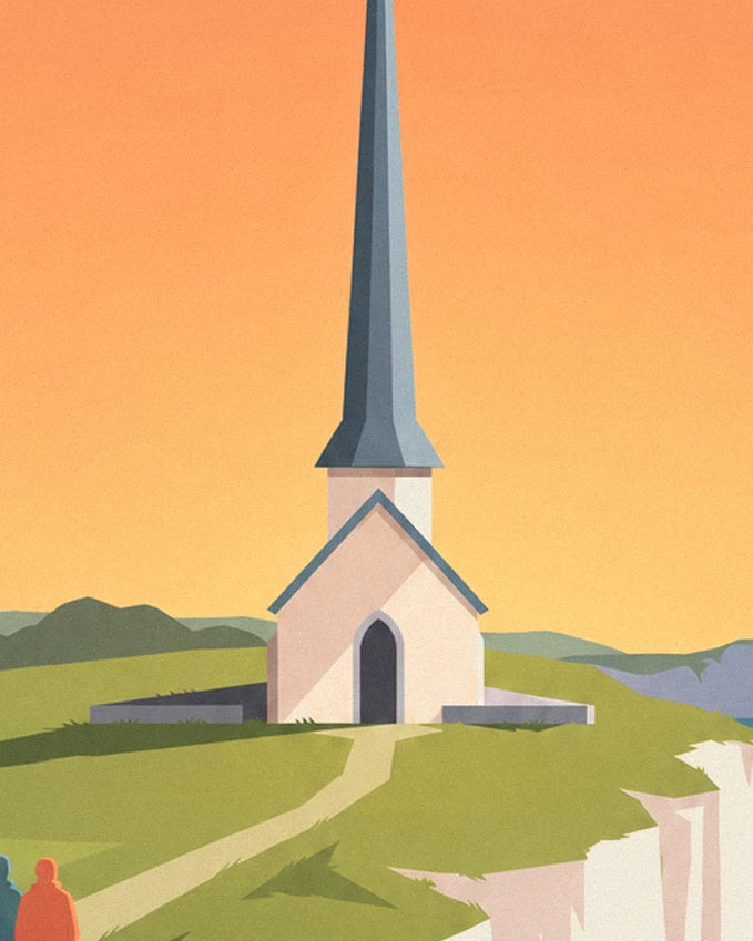 La chapelle blanche et son clocher pointu ardoise, sur l'herbe devant un ciel orangé
