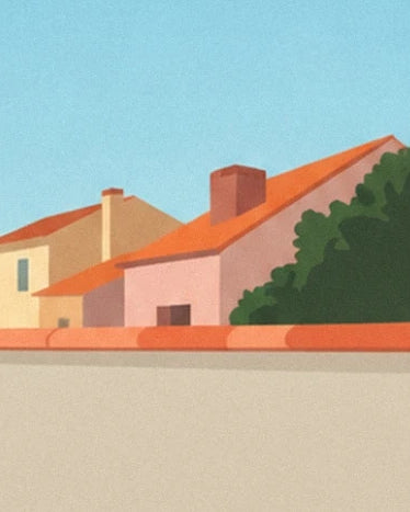 The orange tiled roofs and pink house beneath a wide blue sky, behind the low wall