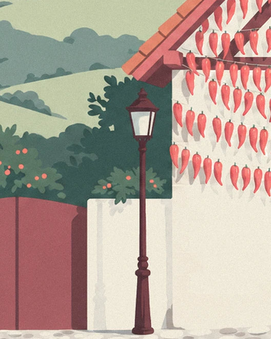 The cast-iron street lamp in front of the façade covered in red chillies, with green hills beyond