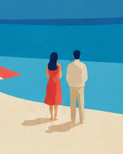 The couple seen from behind on the sand, she in a red dress and he in a beige jumper, facing the sea