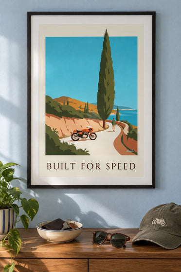 Orange café racer motorcycle poster on a coastal road: framed on the wall