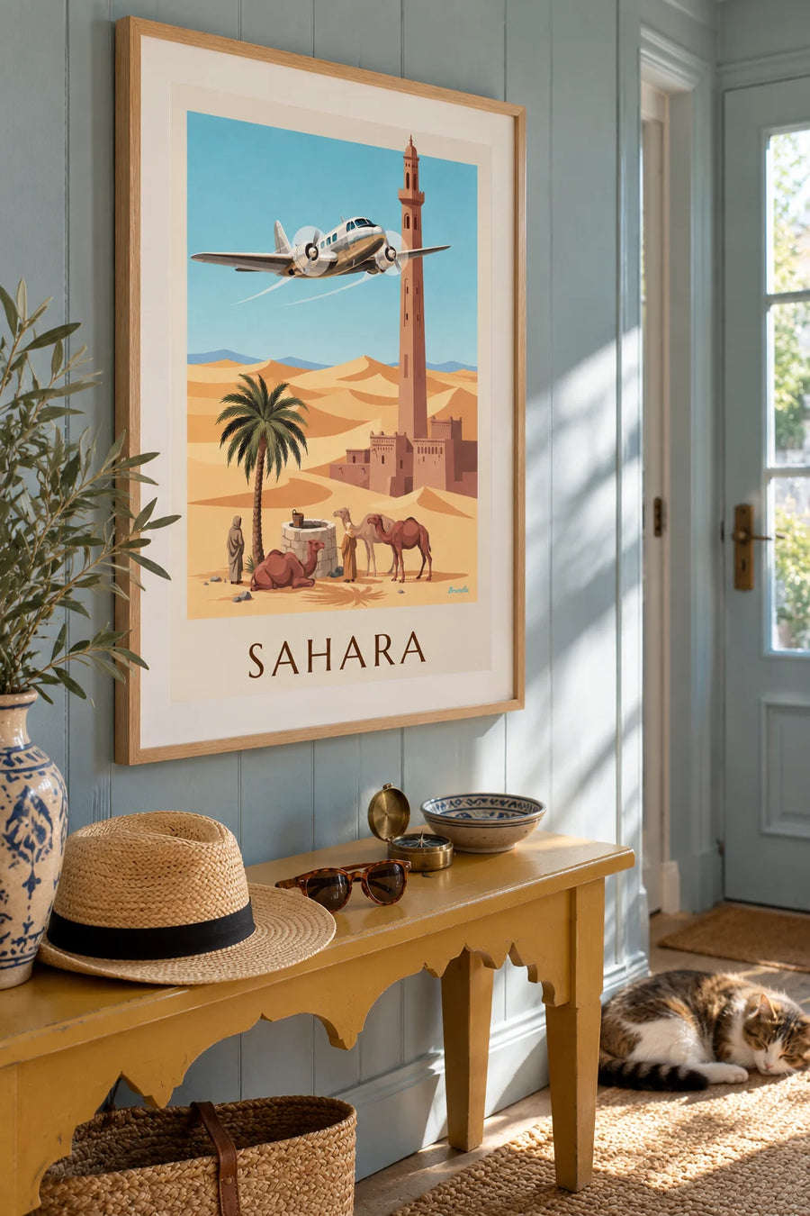 Poster of a three-engine plane flying over an oasis and the Sahara dunes: framed on the wall